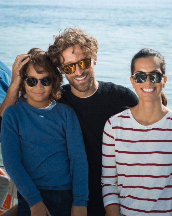 Familie purtând lentile Essilor cu Xperio Polarised pe malul mării